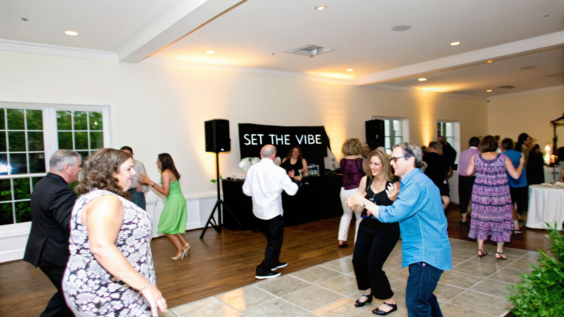 Guests dancing and having fun at a lively indoor party with a DJ booth.