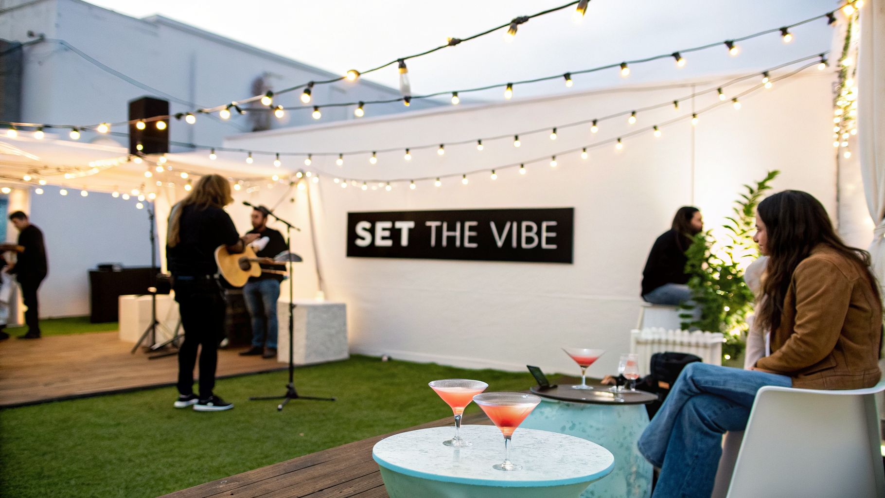An outdoor event space with a band performing live, string lights, and guests enjoying cocktails.