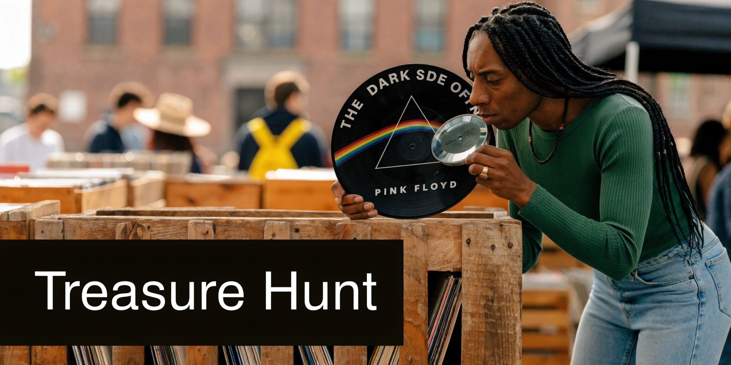 A person with braided hair examining a Pink Floyd vinyl record with a magnifying glass at a market.