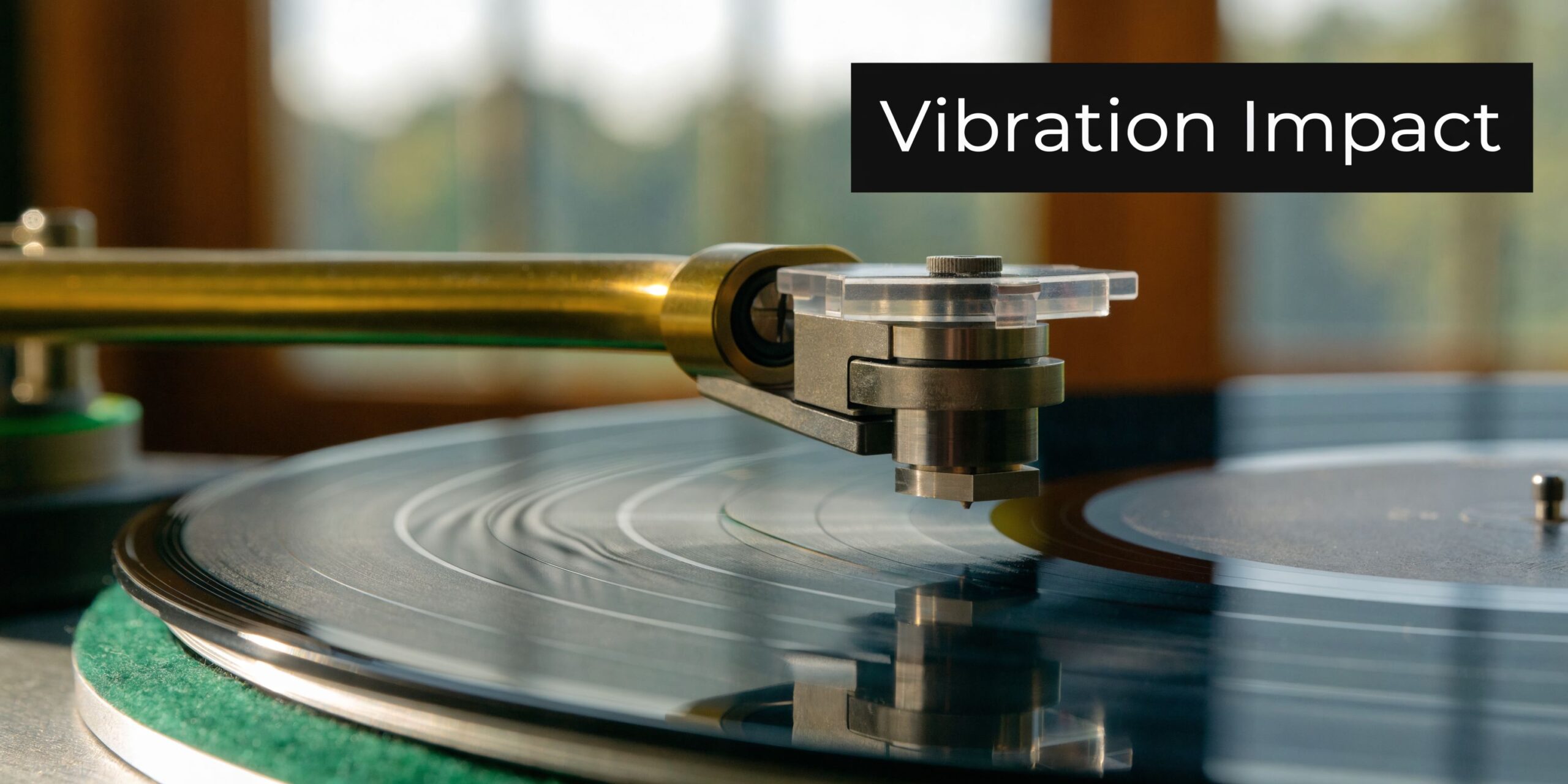 A close-up side view of a high-end record player tonearm tracking the grooves of a black vinyl record.