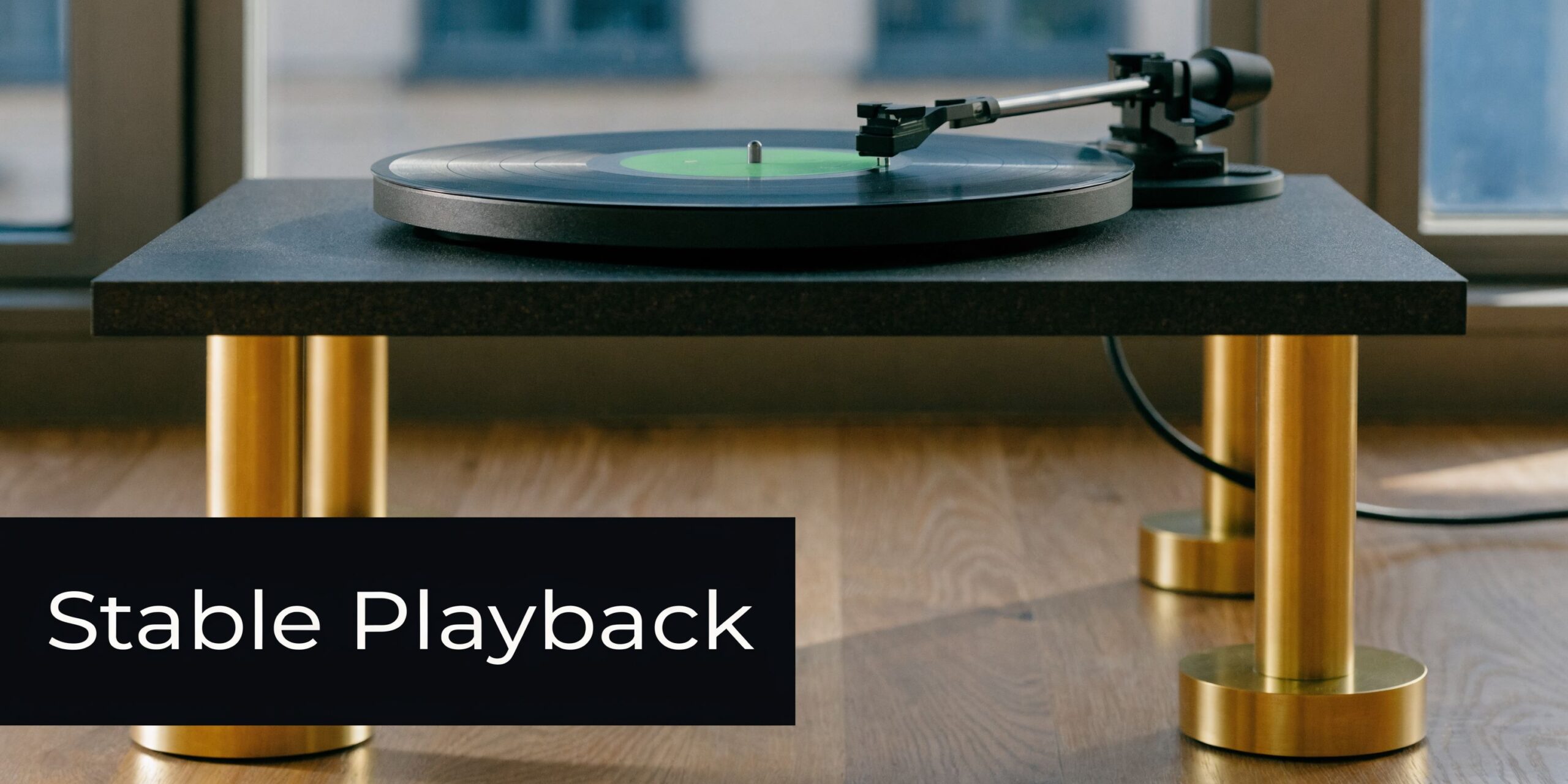 A modern vinyl record player sits on a stylish shelf with brass legs on a wooden floor.